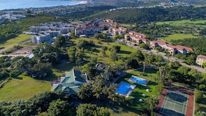 An aerial view of a residential area with multiple buildings, a swimming pool, and a tennis court. - Castleton (Plettenberg Bay)
