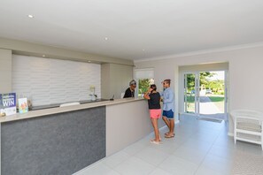 A reception area with a counter, a receptionist, and guests conversing. - Castleton (Plettenberg Bay)