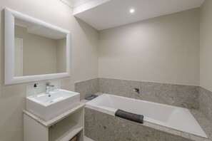 A modern bathroom with a white sink, a large mirror, and a freestanding bathtub. - Castleton (Plettenberg Bay)