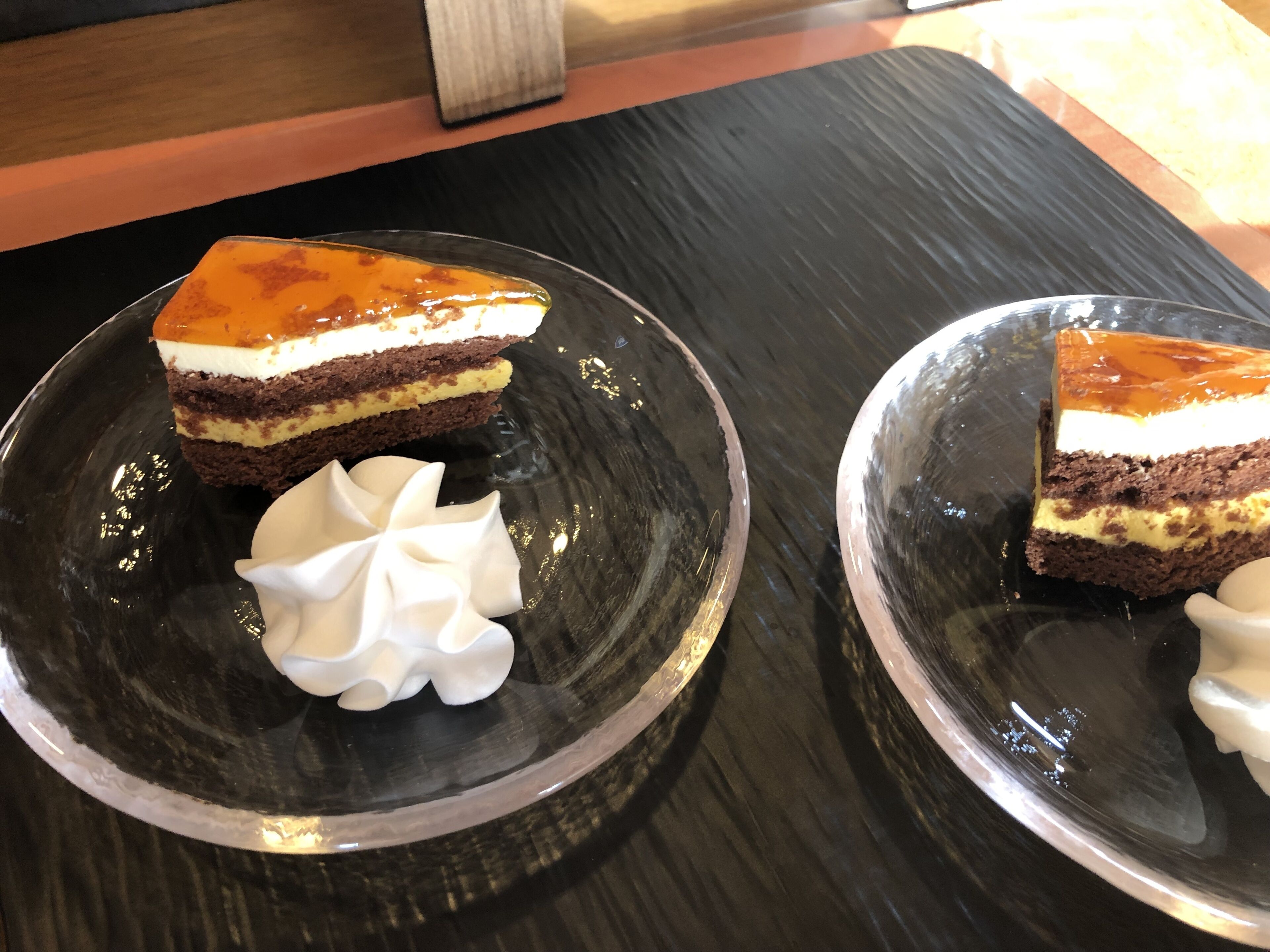 Two glass plates with slices of layered cake and whipped cream.