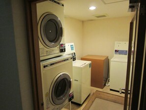 A laundry room with two front-loading washing machines and a dryer.