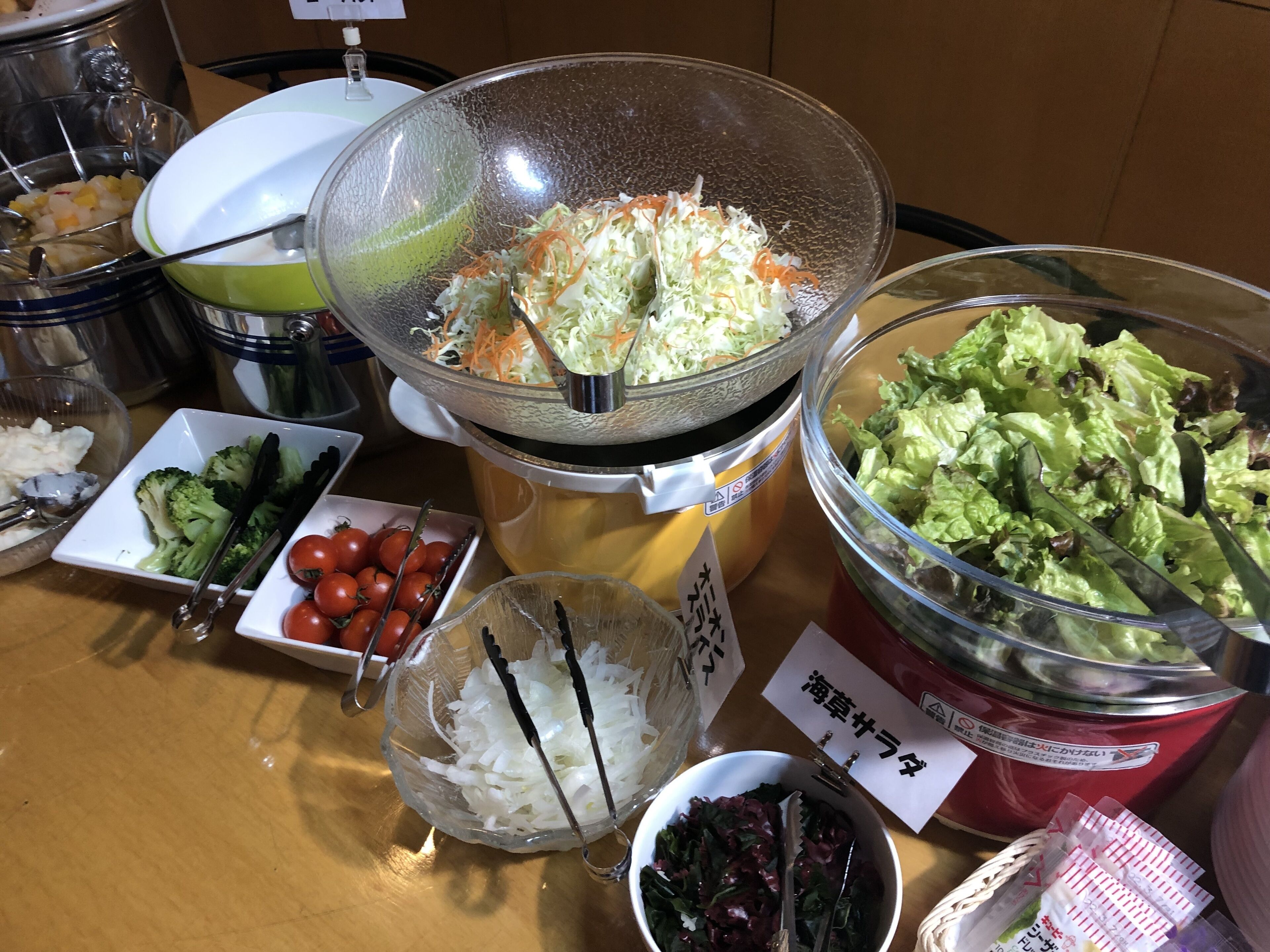 Noutopöydässä on tarjolla erilaisia ruokia, kuten coleslaw-salaattia, salaattia, tomaatteja ja muita salaatteja.