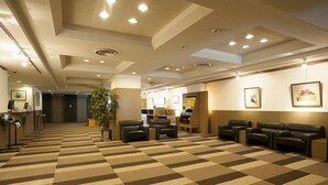 Een hotellobby met een receptiebalie, een zithoek en een incheckplein.