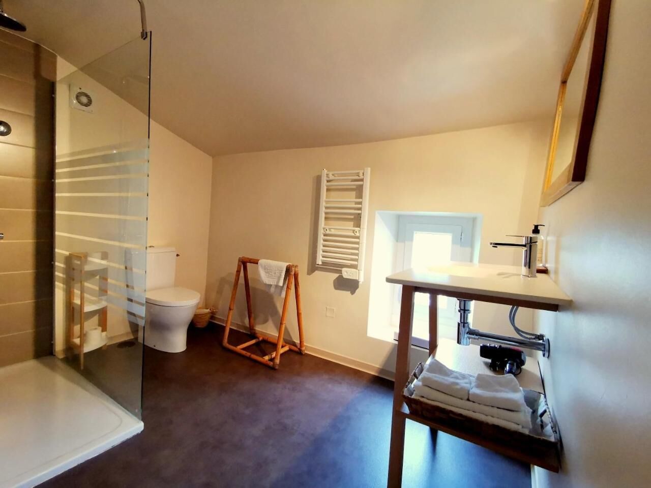 Ein Badezimmer mit Duschkabine aus Glas, Toilette, Handtuchhalter und Waschbecken mit Spiegel.