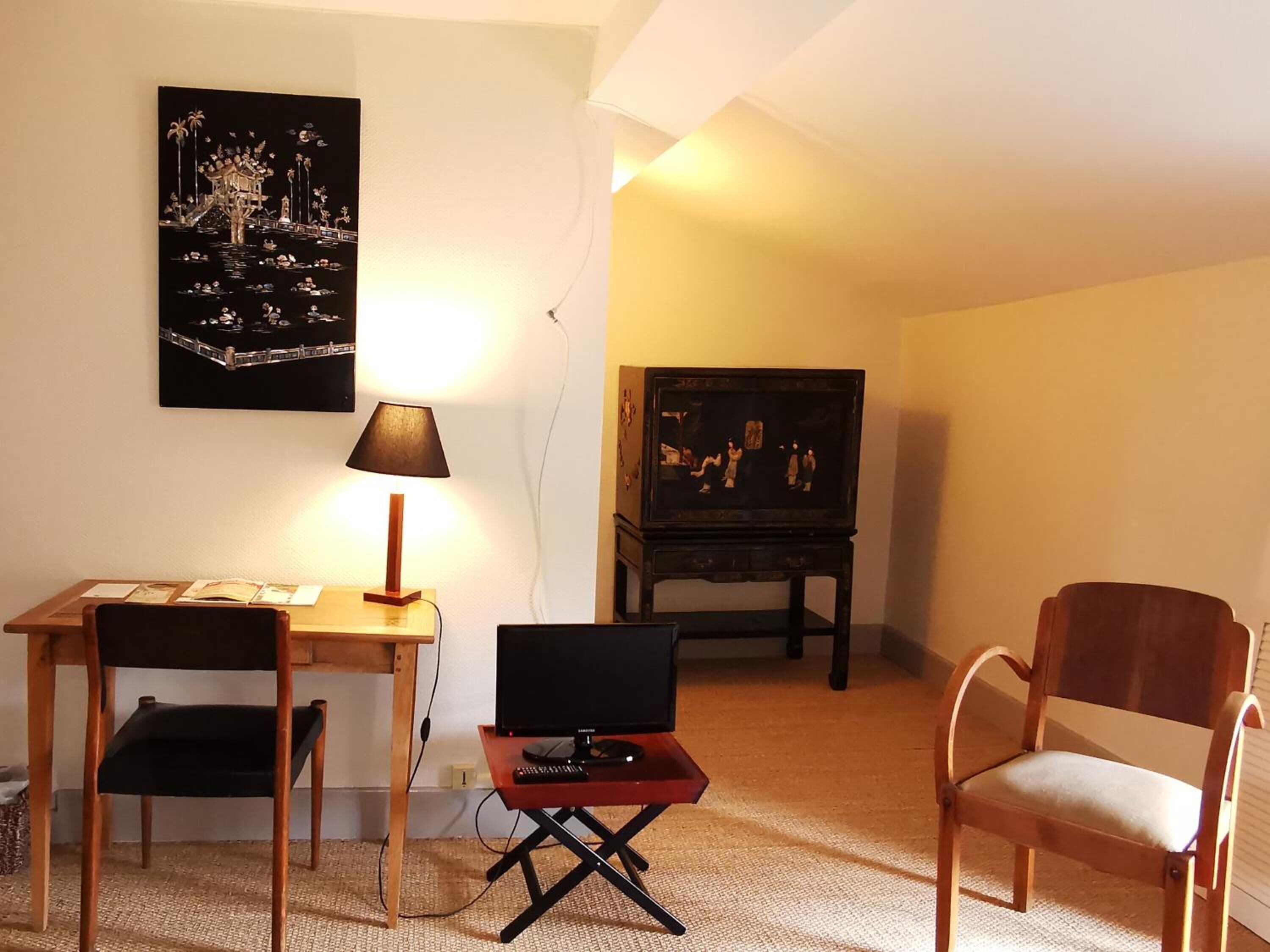 A cozy living room with a wooden table, a TV on a stand, and a chair.