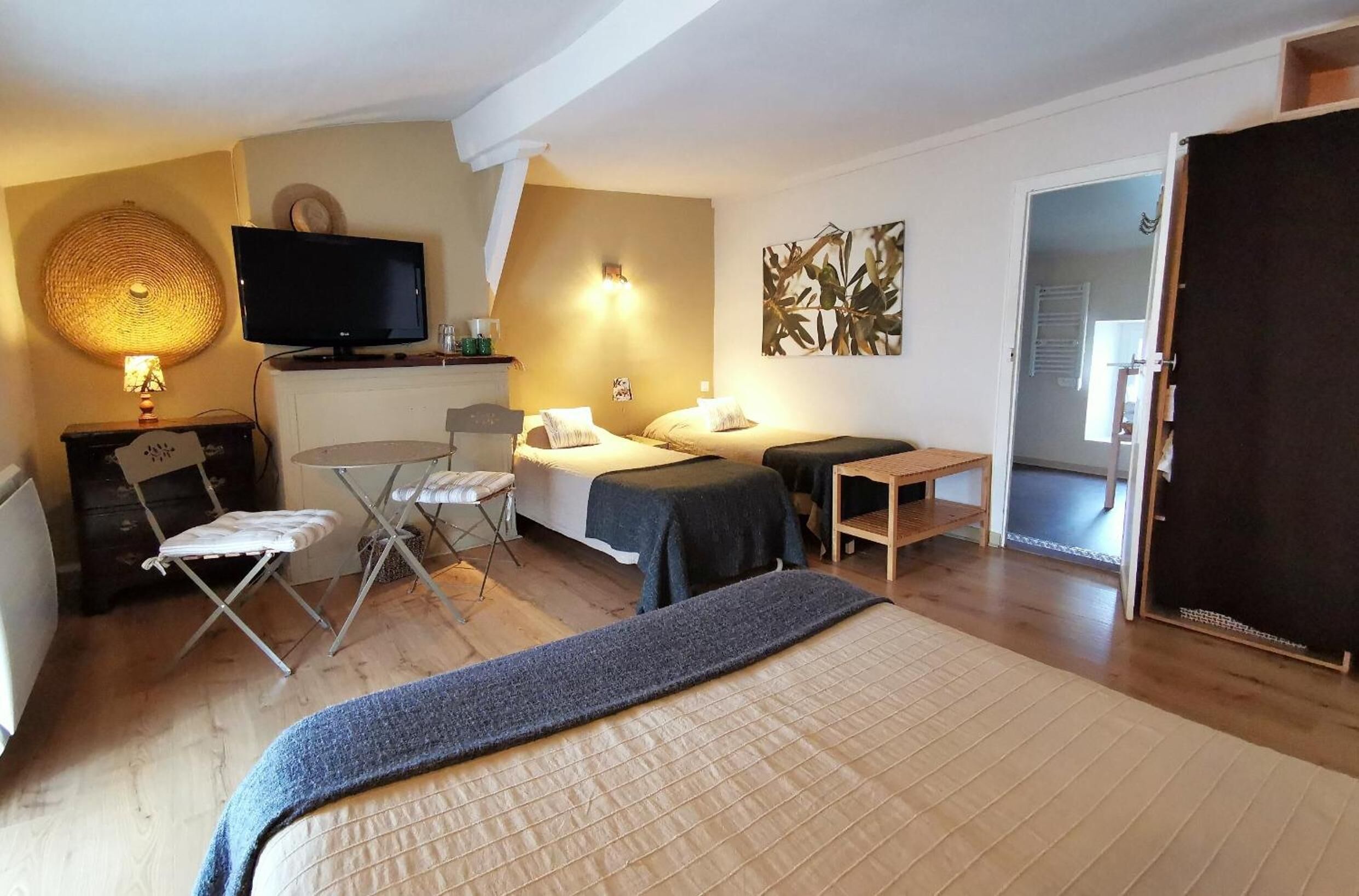 Ett mysigt hotellrum med en säng, ett skrivbord, en stol, en tv och en vägglampa.