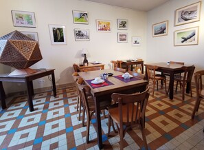 A dining area with multiple tables and chairs, framed pictures on the walls, and a patterned floor. - Logis Auberge La Barguillère (Saint-Pierre-de-Riviere)