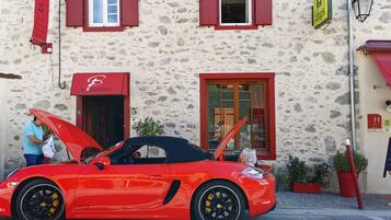 A red sports car parked in front of a building with a stone facade, red shutters, and a sign for 'la Barguillerie'.
