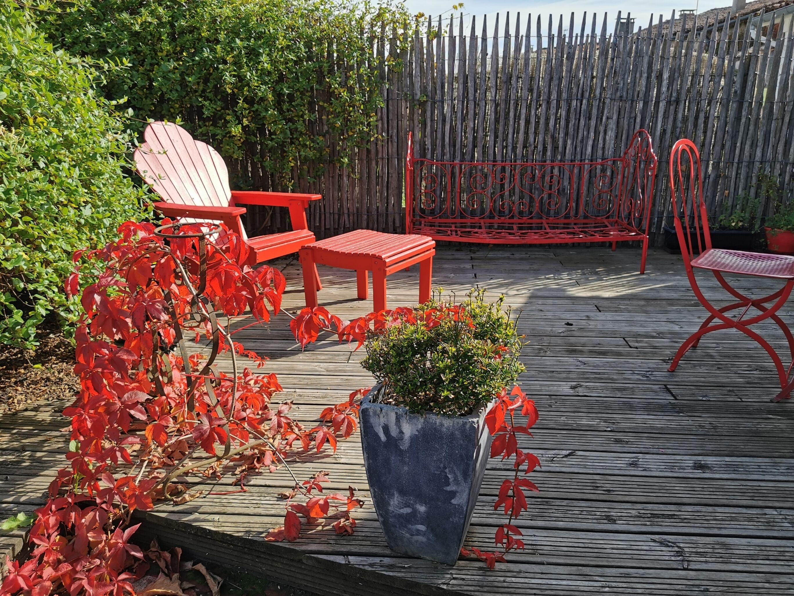 A wooden deck with red outdoor furniture, including chairs and a table.