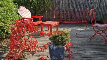 A wooden deck with red outdoor furniture, including chairs and a table.