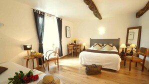 Una habitación de hotel con cama, escritorio, silla, lámpara y espejo.