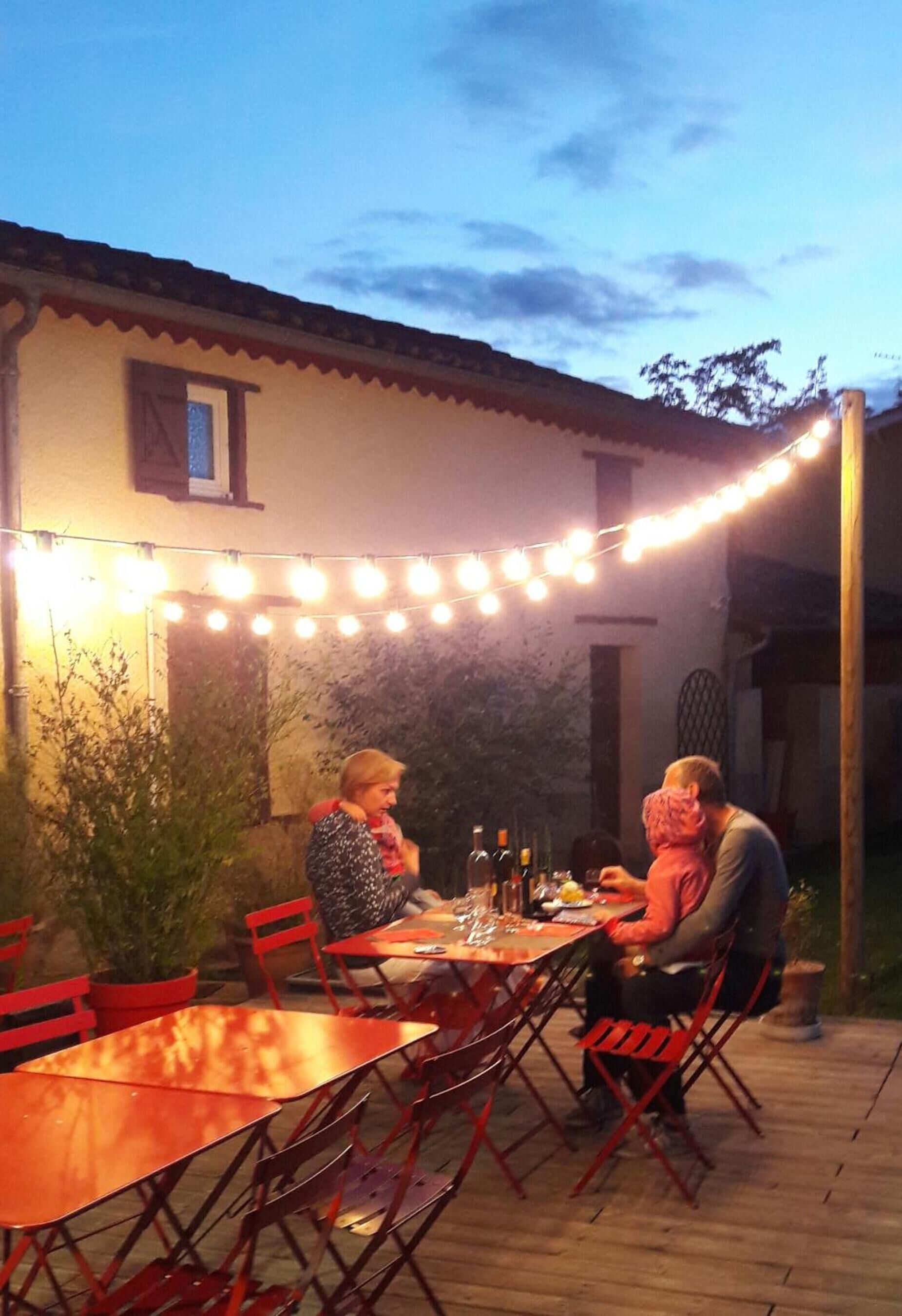 An outdoor patio with a table and chairs, string lights, and potted plants.