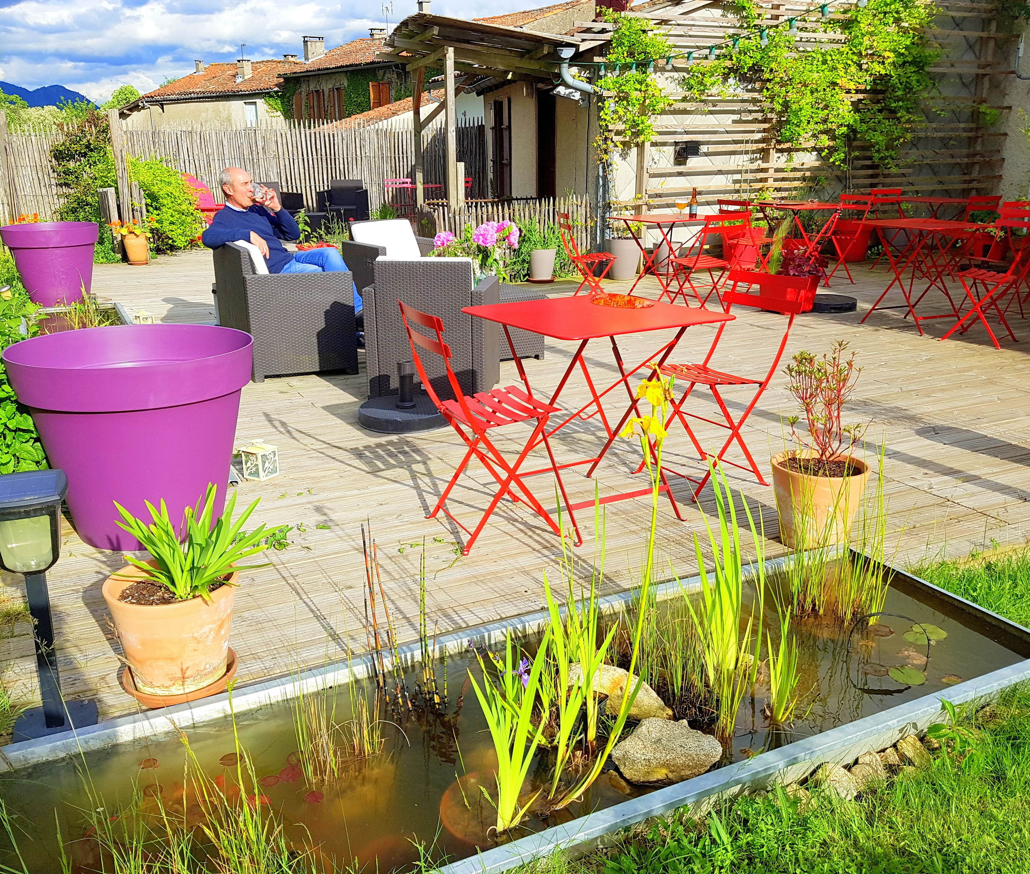 A patio with outdoor furniture, a small pond, and potted plants.
