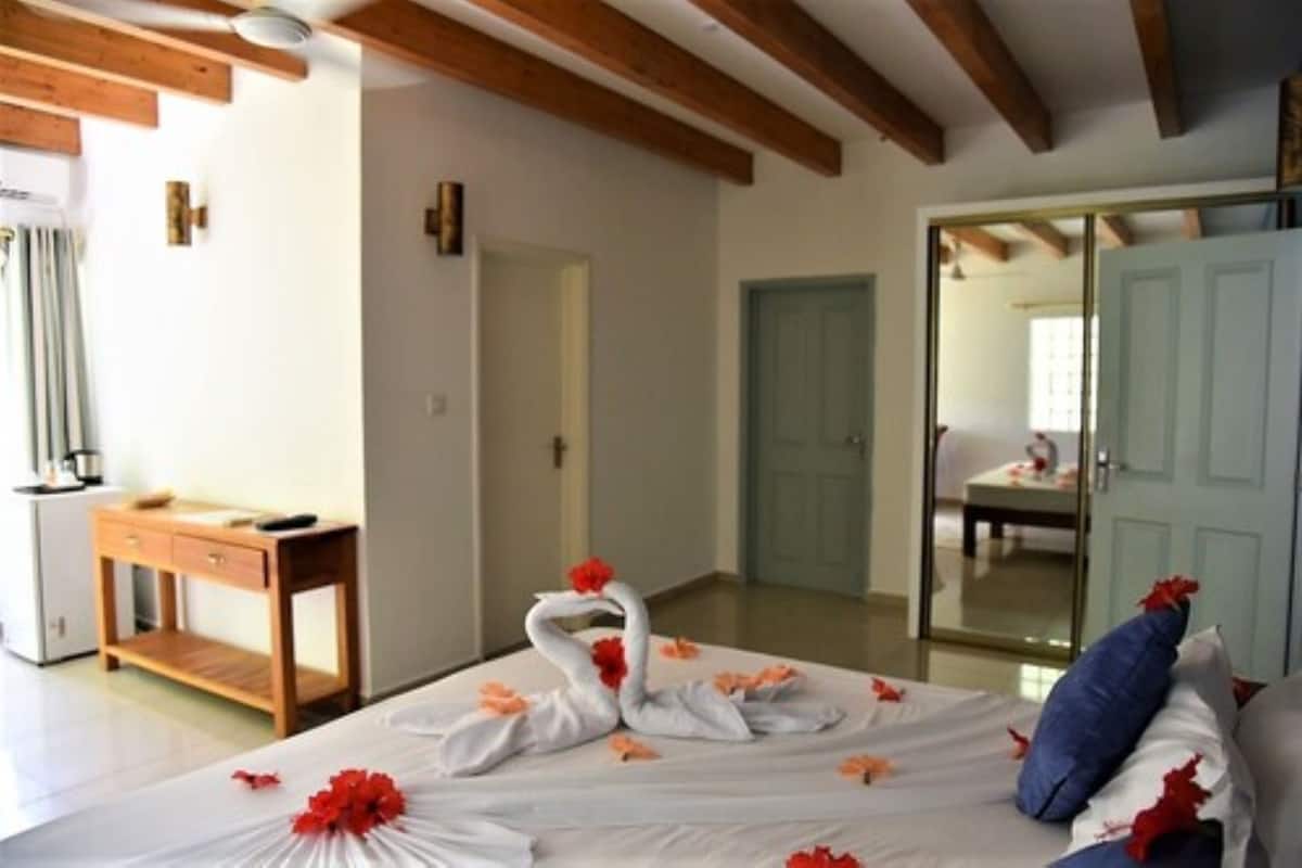 Una habitación de hotel con una cama, un escritorio de madera, un armario y una puerta que da a otra habitación.