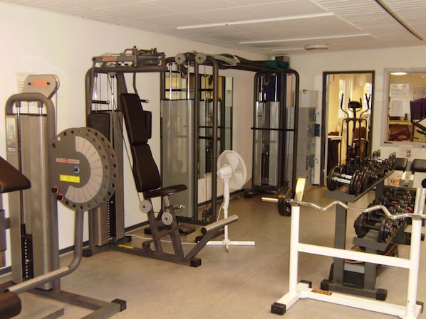 Un gimnasio con diversos equipos de ejercicio, incluyendo máquinas de pesas y pesas libres.