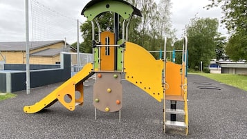 A playground with a climbing structure, a slide, and a ladder.