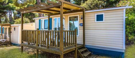 A mobile home with a wooden deck and a covered porch.