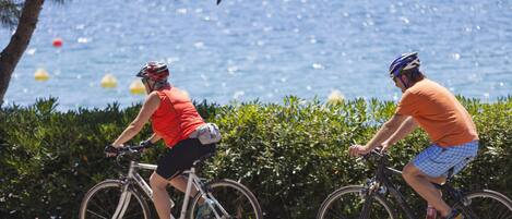 Deux cyclistes sur un sentier, avec une étendue d’eau et de la végétation en arrière-plan.