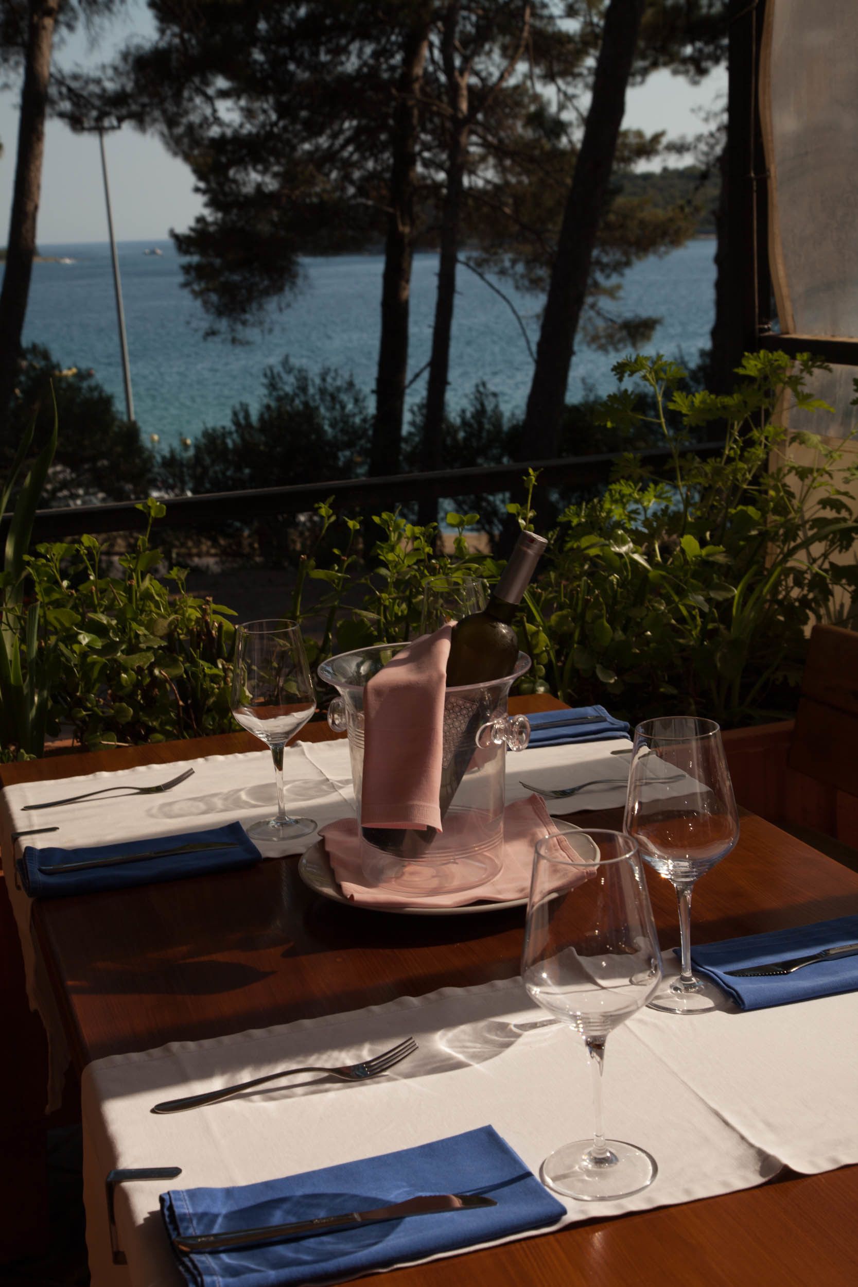 A table set for dining with a view of the sea, a bottle, and a pitcher.