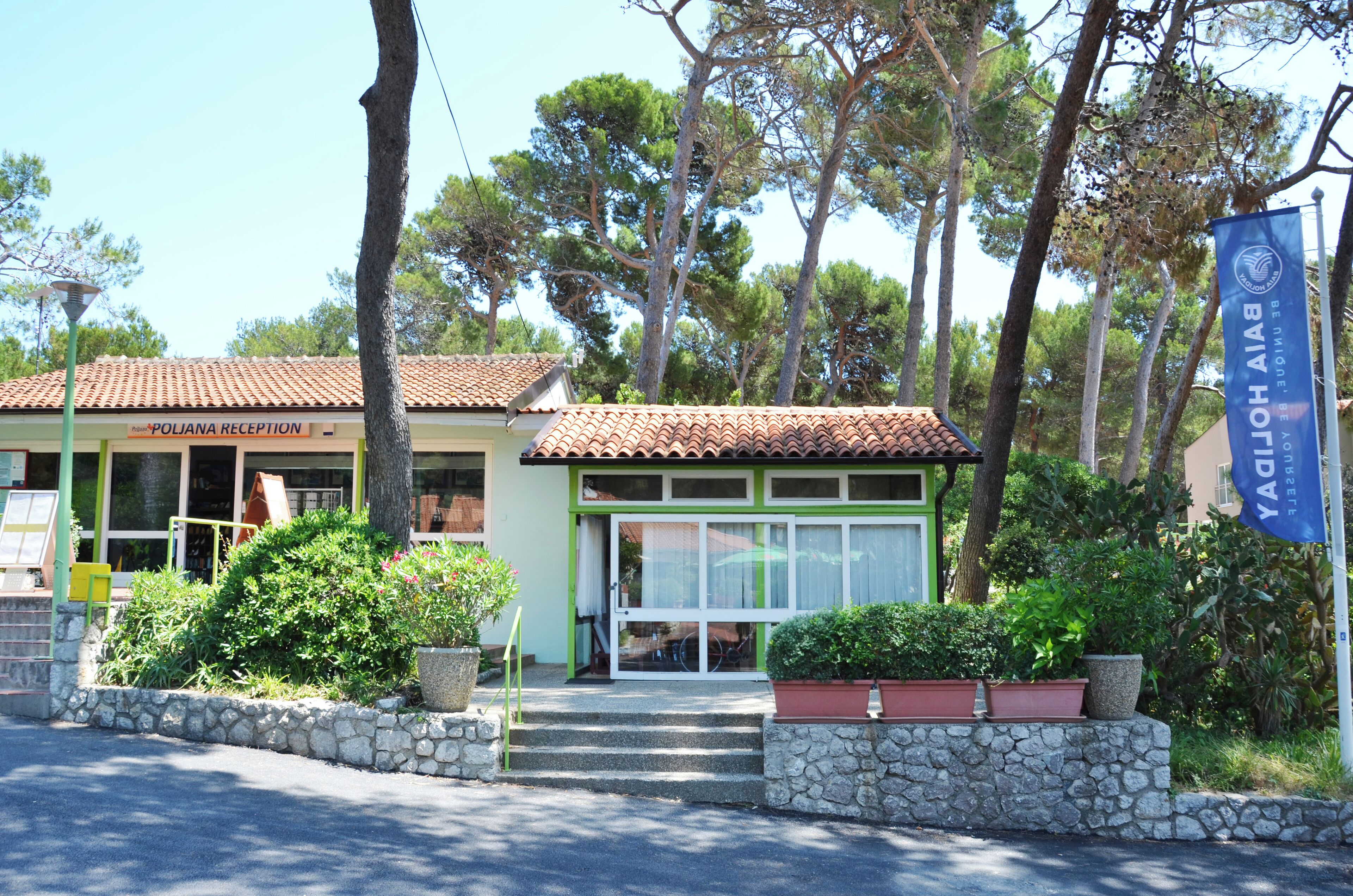 A building with a reception area labeled "POLIANA RECEPTION" and a sign for "BAY HOLIDOMES".