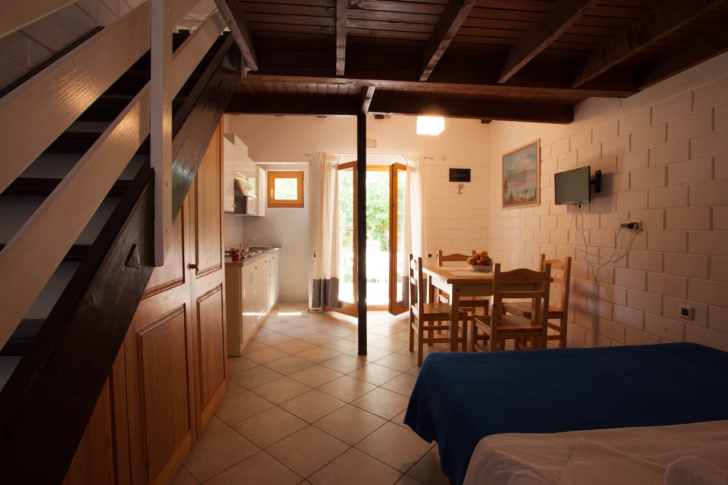 Un dormitorio con cama, una escalera de madera, una cocina y un comedor.