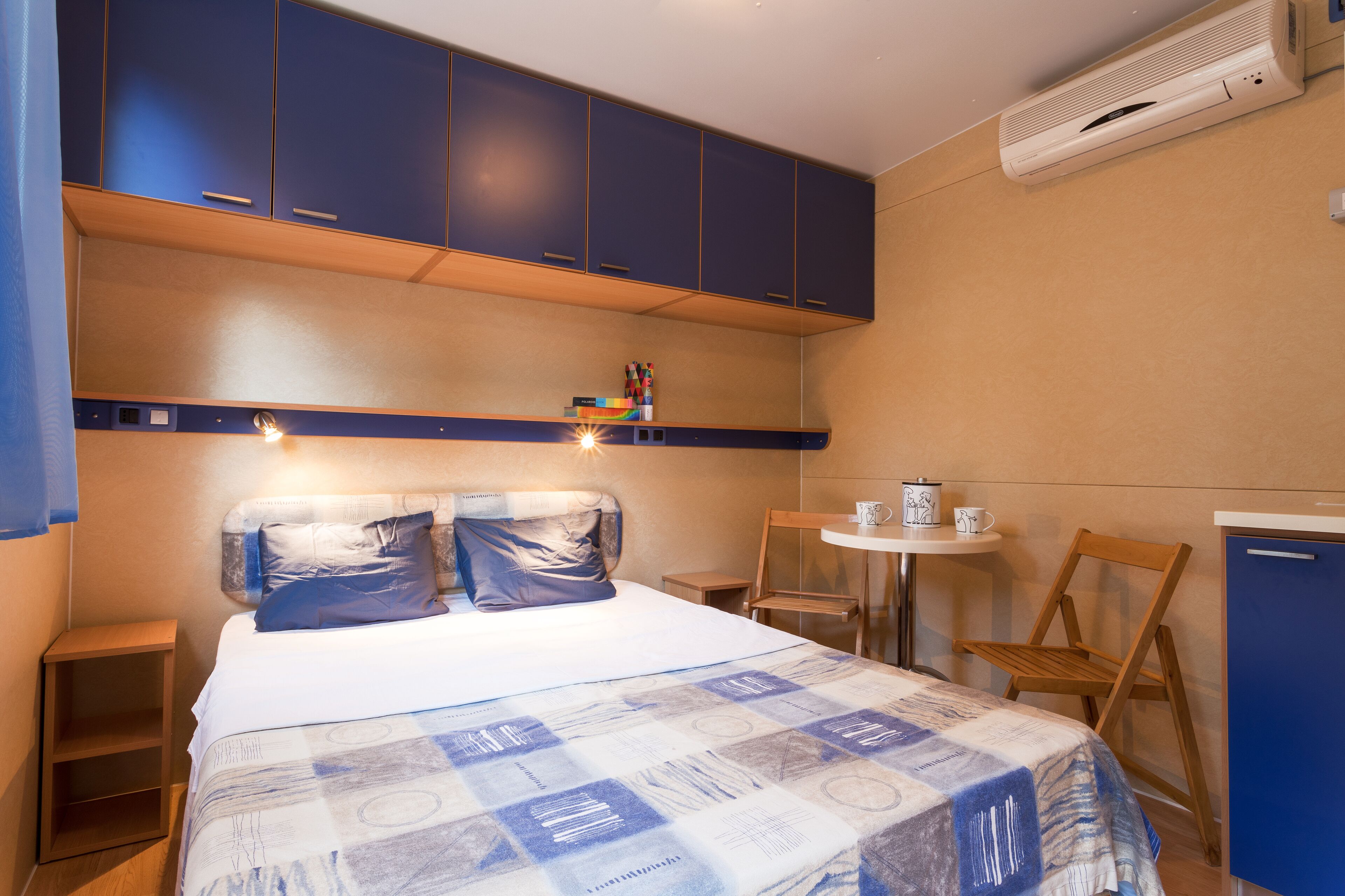 Een slaapkamer met een bed, een tafeltje, een stoel en een kledingkast.