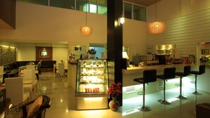 Un hall d’hôtel moderne comprenant un comptoir d’accueil, un espace salon et un présentoir de desserts.