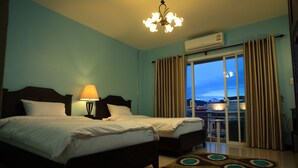 Une chambre d’hôtel avec deux lits, un lustre, un appareil de climatisation et une vue sur un balcon.