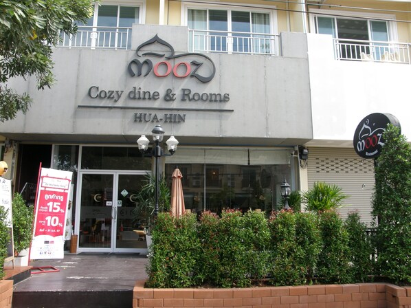 Un bâtiment avec une enseigne indiquant « Moox Cozy dine & Rooms » et « HUA-HIN ».