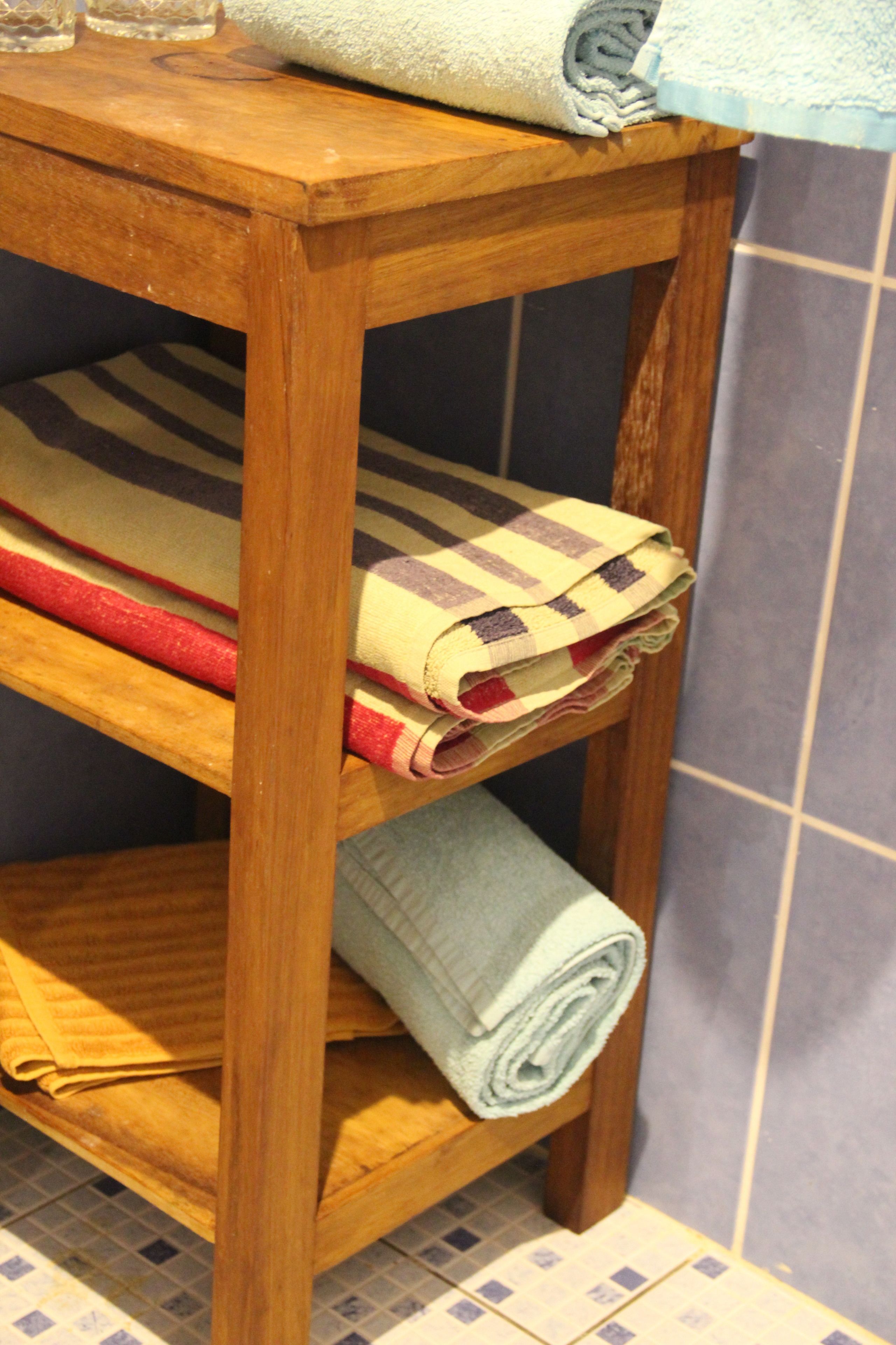 A wooden shelf with folded towels in various colors.