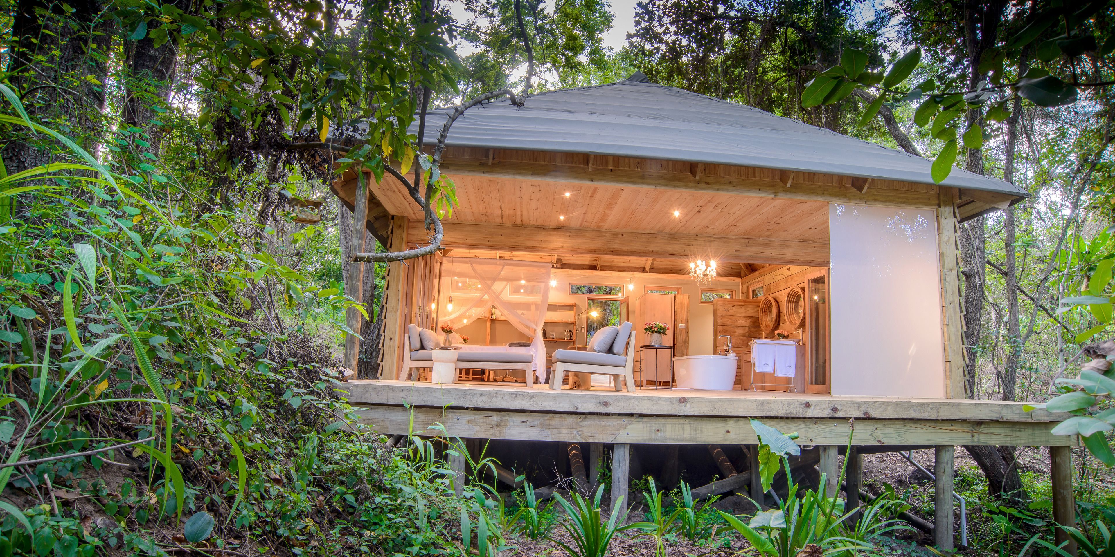 Una cabaña de madera con un balcón, baño y zona de estar con mesa y sillas.