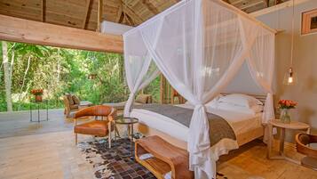 A spacious bedroom with a canopy bed, wooden flooring, and a view of the outdoors.