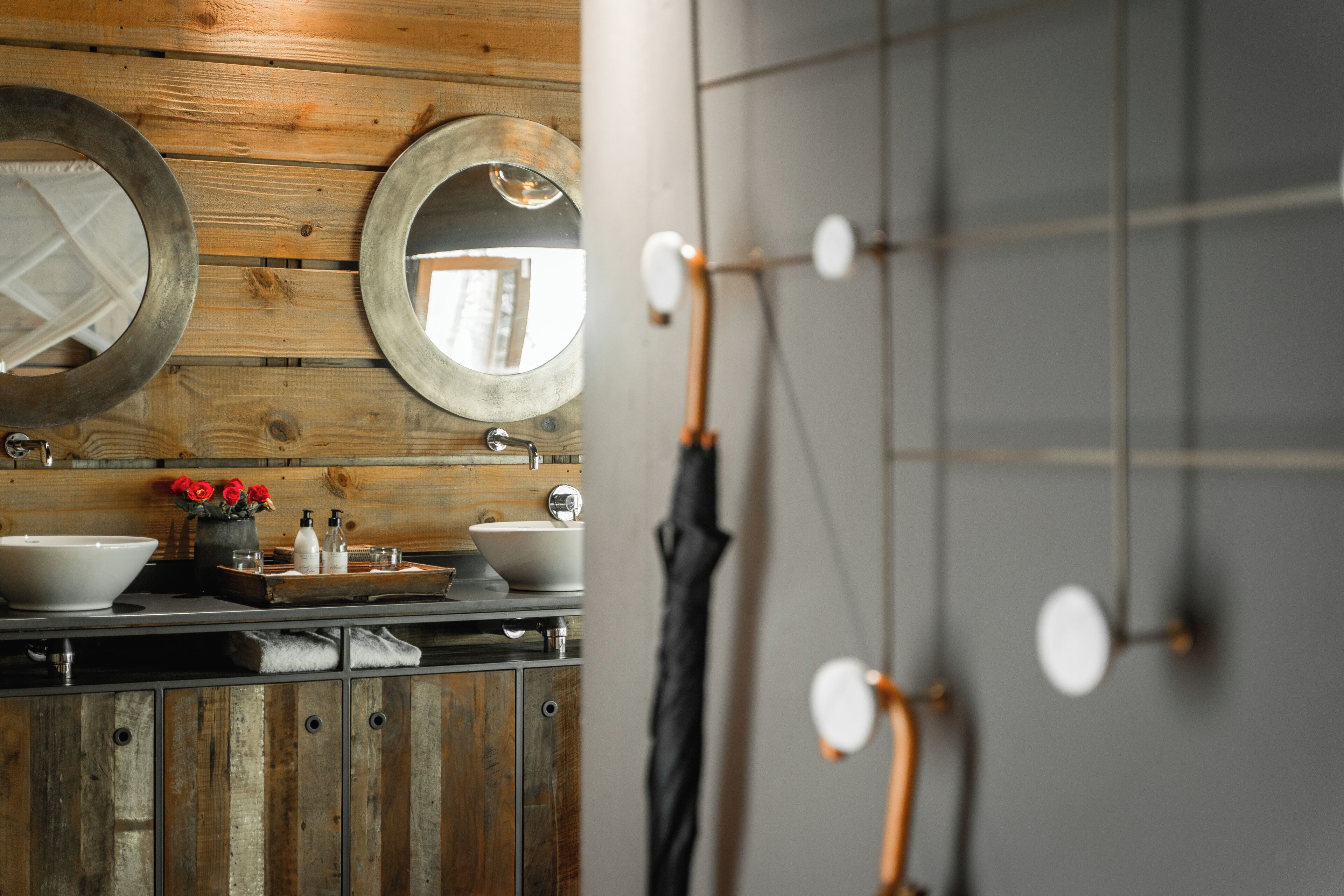 Un baño con paneles de madera, un lavabo y dos espejos.