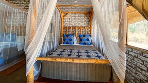 A bed with a canopy, a brick wall, and a wooden ceiling. - Gwango Heritage Resort (Dete)