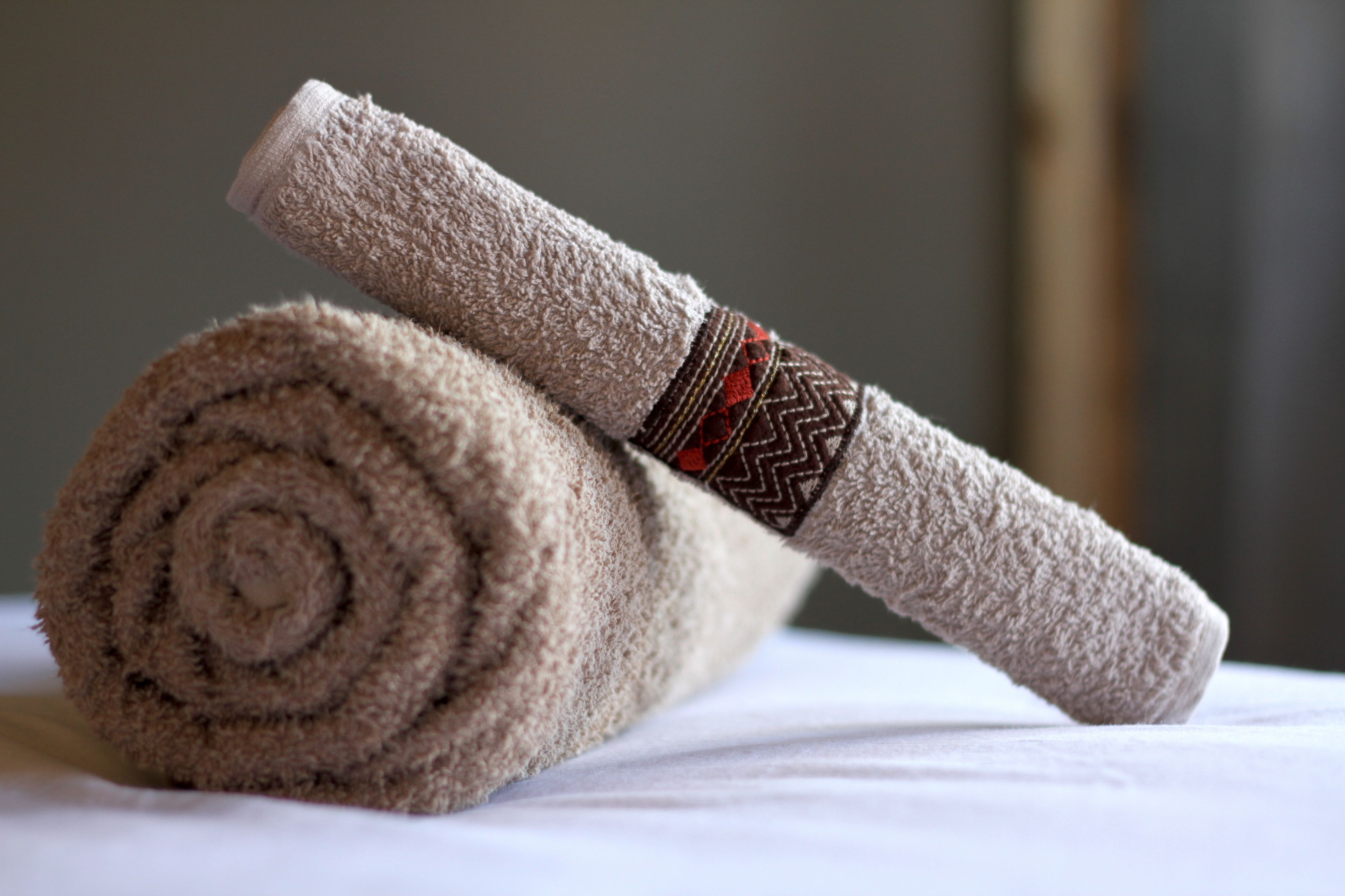 A rolled towel with a patterned band on a white surface.