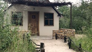 A small, rustic house with a stone wall entrance, a wooden door, and a window. - Gwango Heritage Resort (Dete)