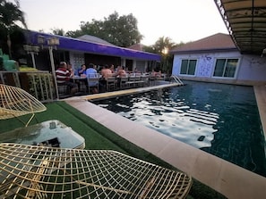 A pool area with lounge chairs, a bar, and a dining area. - Head Rock Home (Hua Hin)