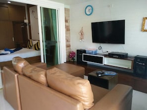 Ein modernes Wohnzimmer mit einer Ledersofa, einem Flachbildfernseher, einer Stereoanlage und einer Schiebetür zu einem Schlafzimmer.