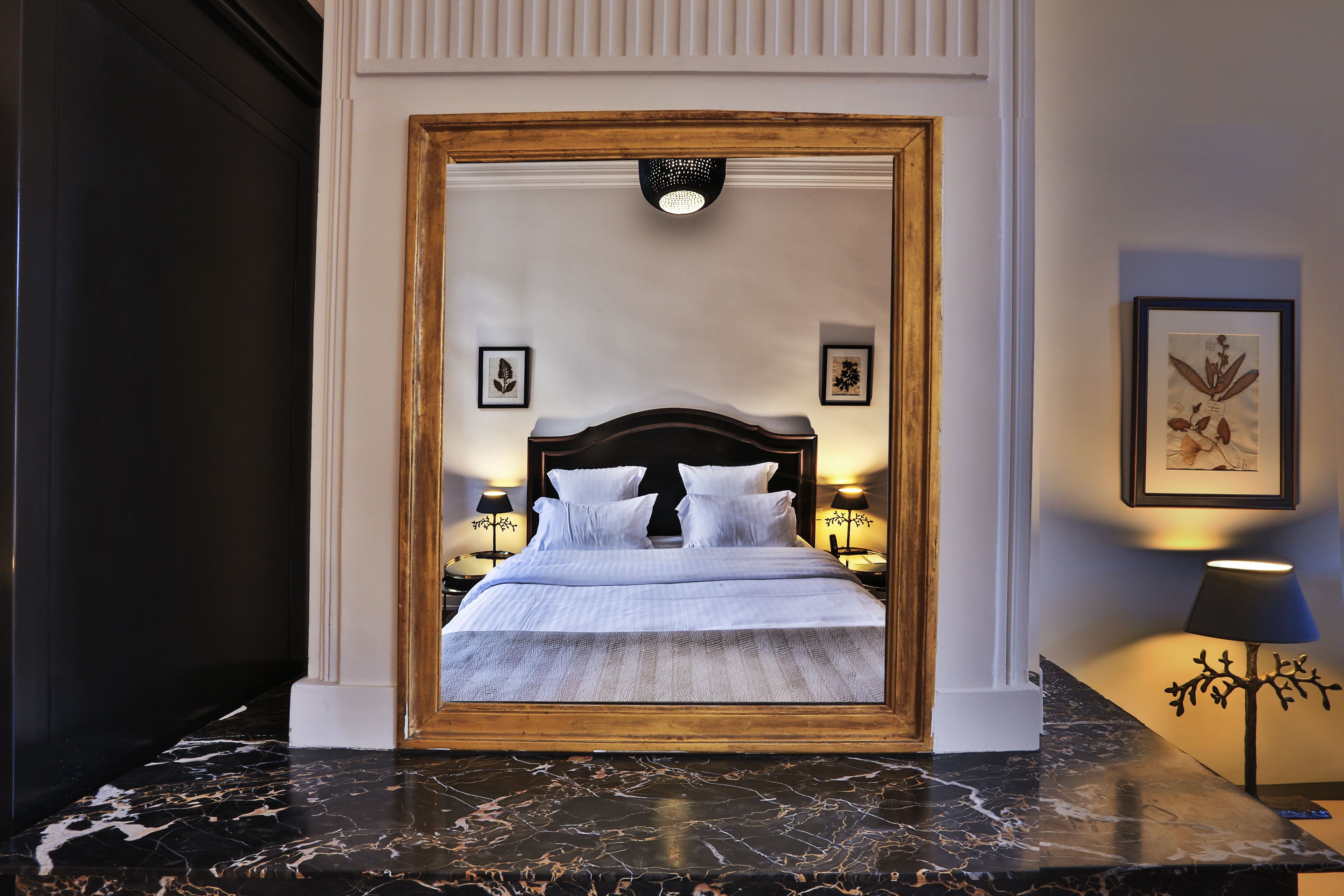 Una cama con cabecera de madera, dos mesitas de noche con lámparas y cuadros en las paredes.