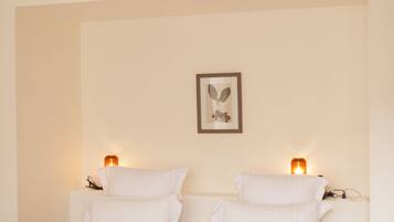 A neatly made bed with a beige bedspread, two bedside lamps, and a framed artwork on the wall.
