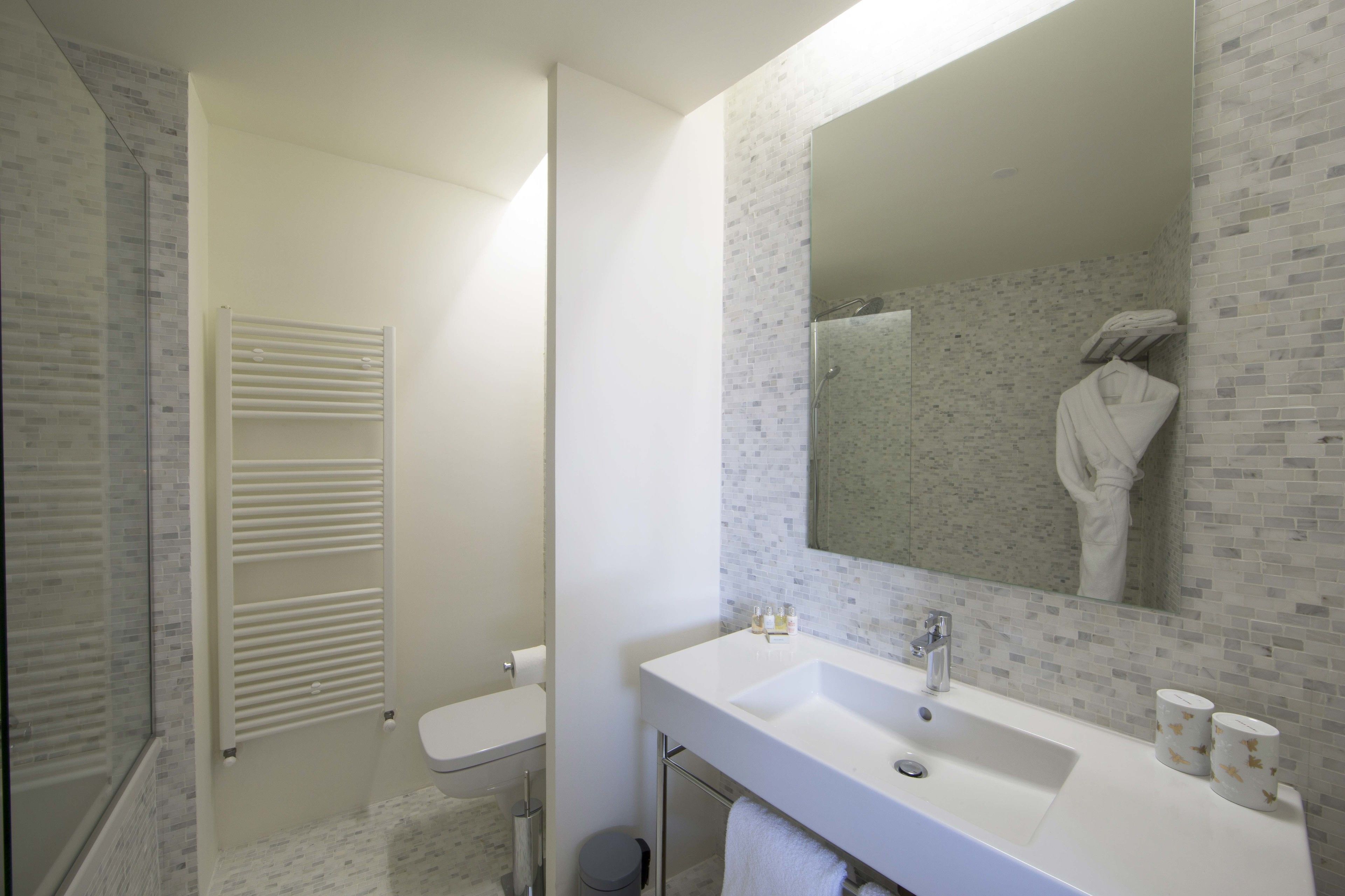 A bathroom with a white sink, a mirror, and a toilet.
