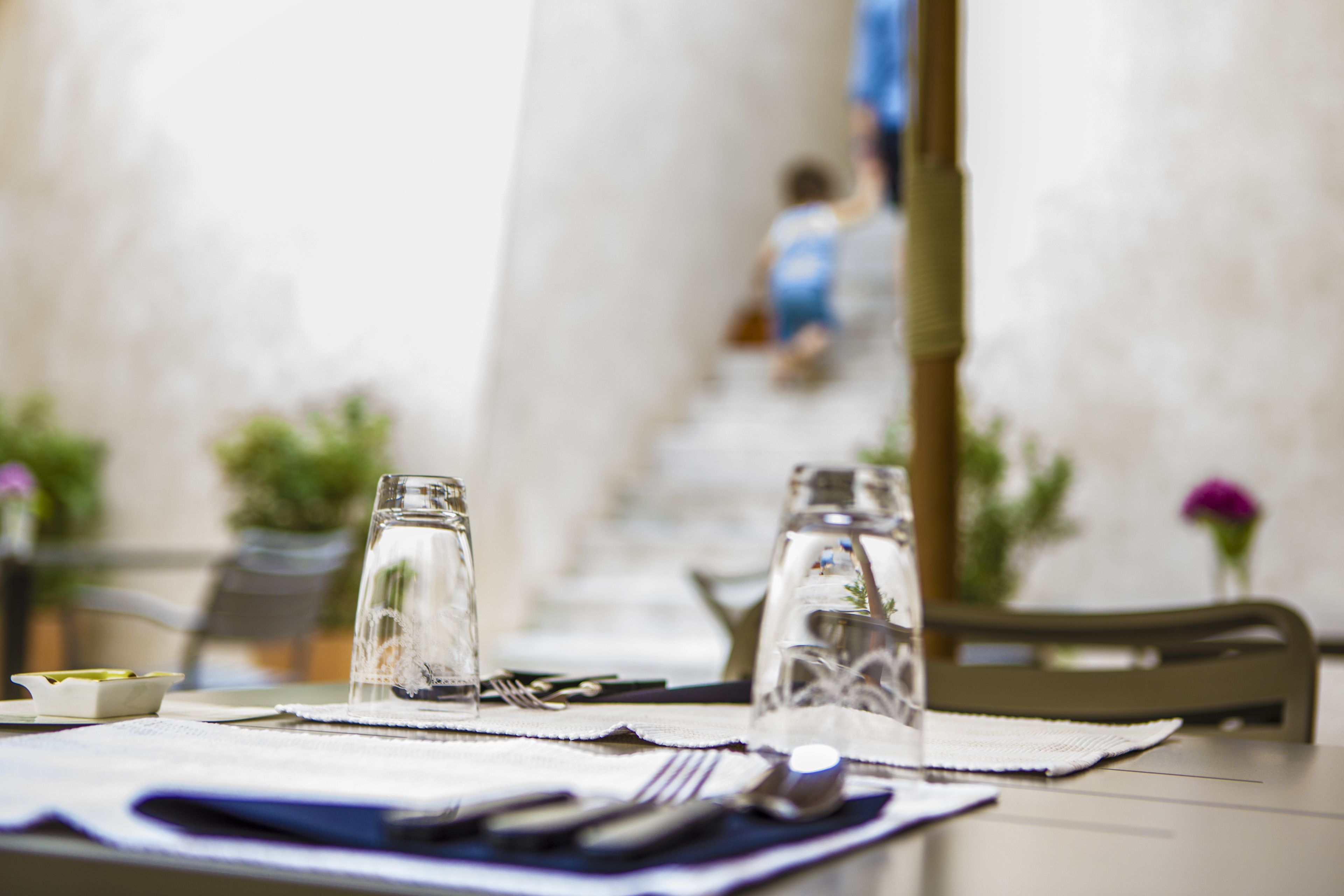 Une table à manger avec un set de table, des couverts et deux verres transparents.