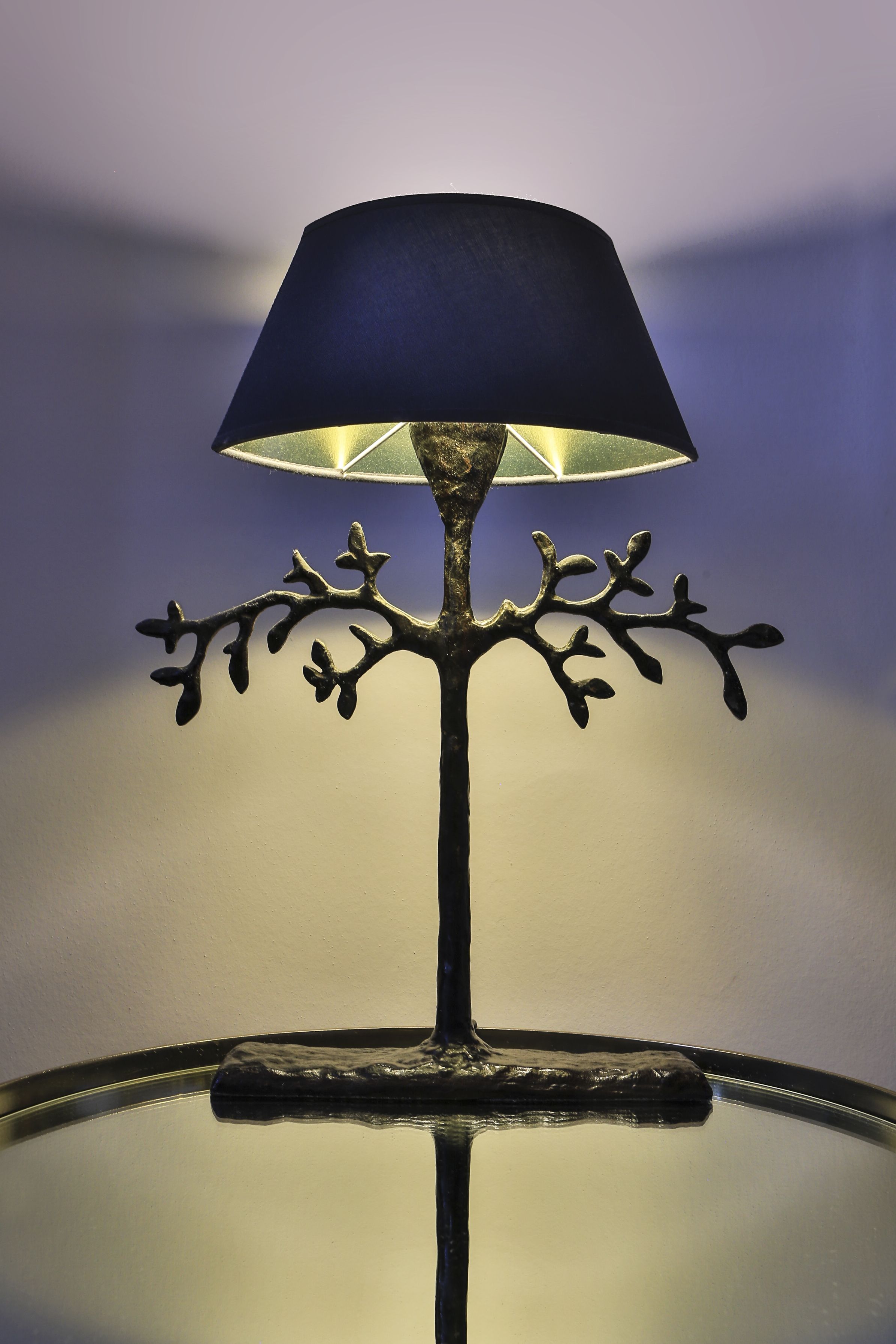 Una lámpara con pantalla oscura y base de metal con forma de rama.