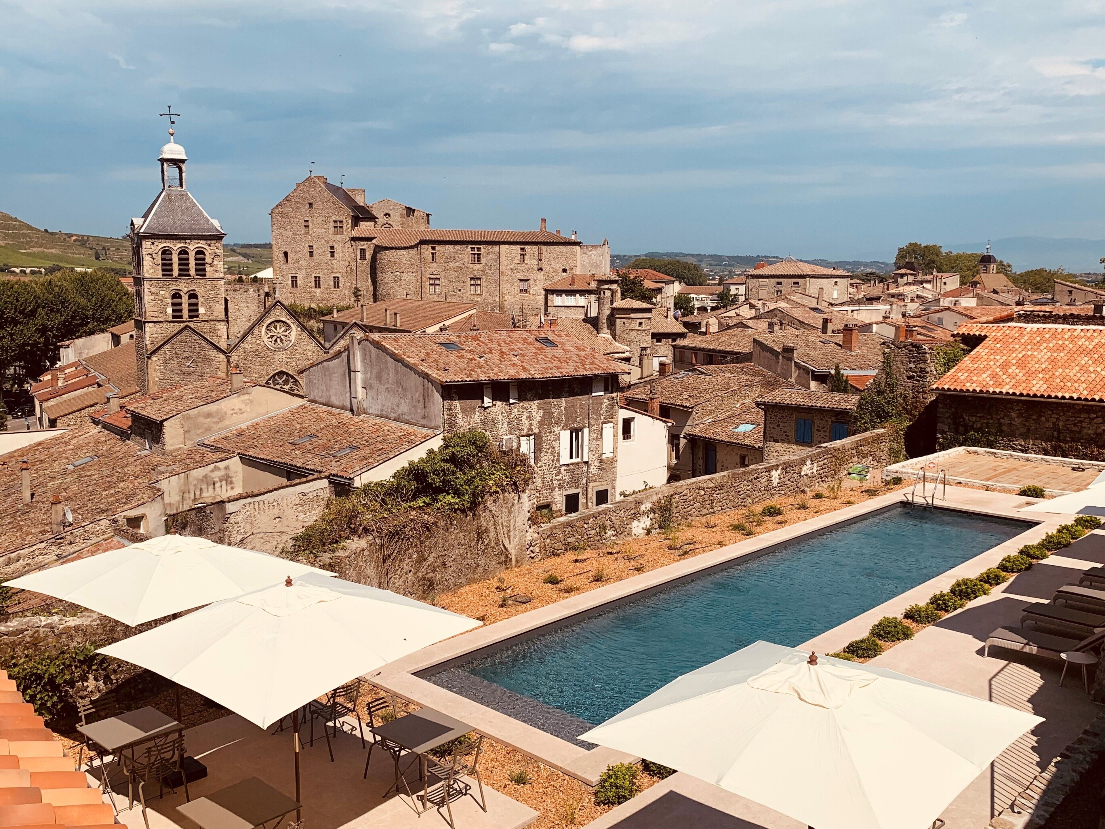Zona de piscina con mobiliario exterior y vistas a edificios históricos.