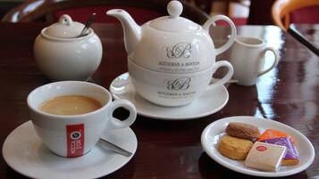 A table with a teapot, cups, and a plate of cookies.