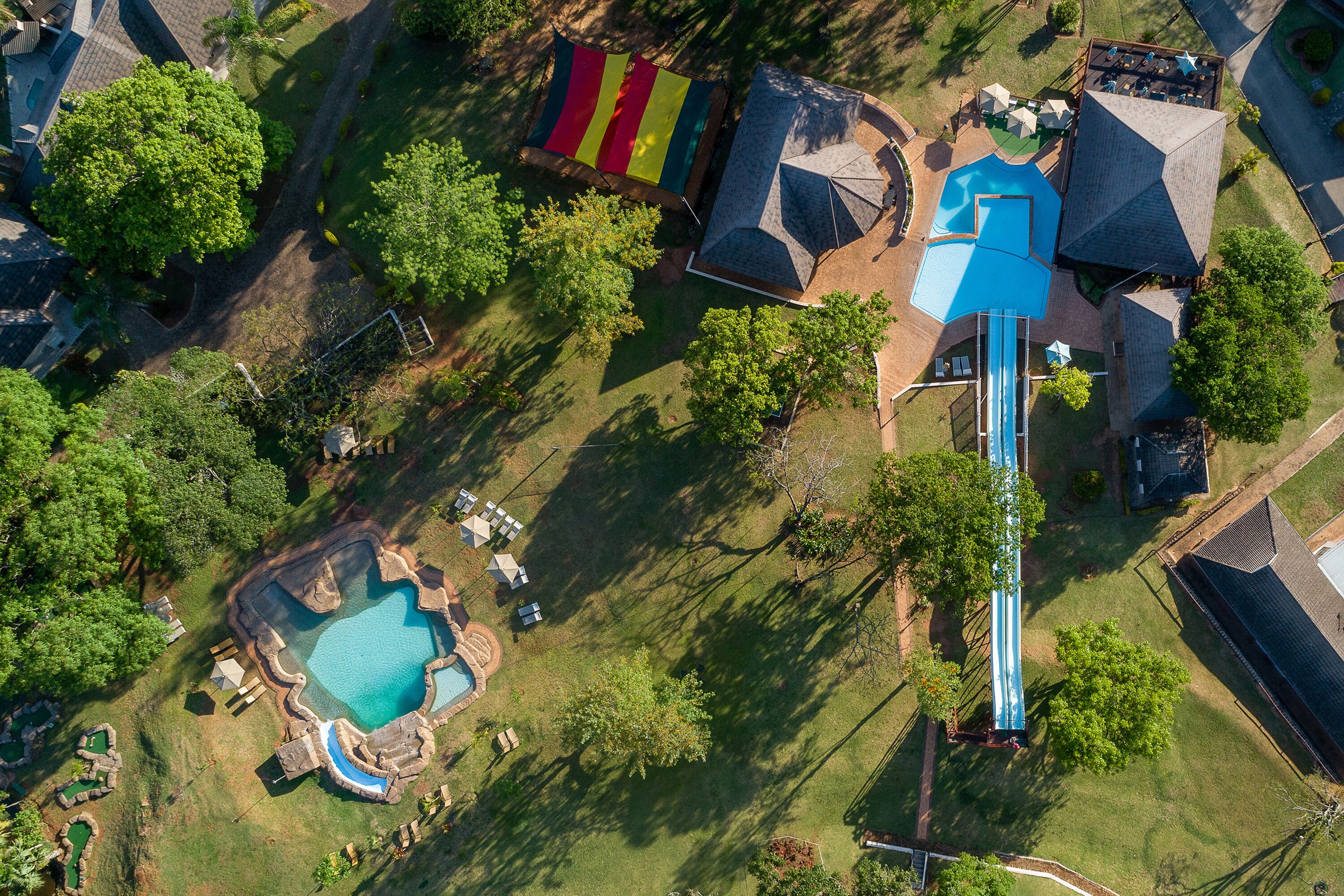 Vista aérea de una zona residencial con piscina, tobogán y un área de juegos colorida.
