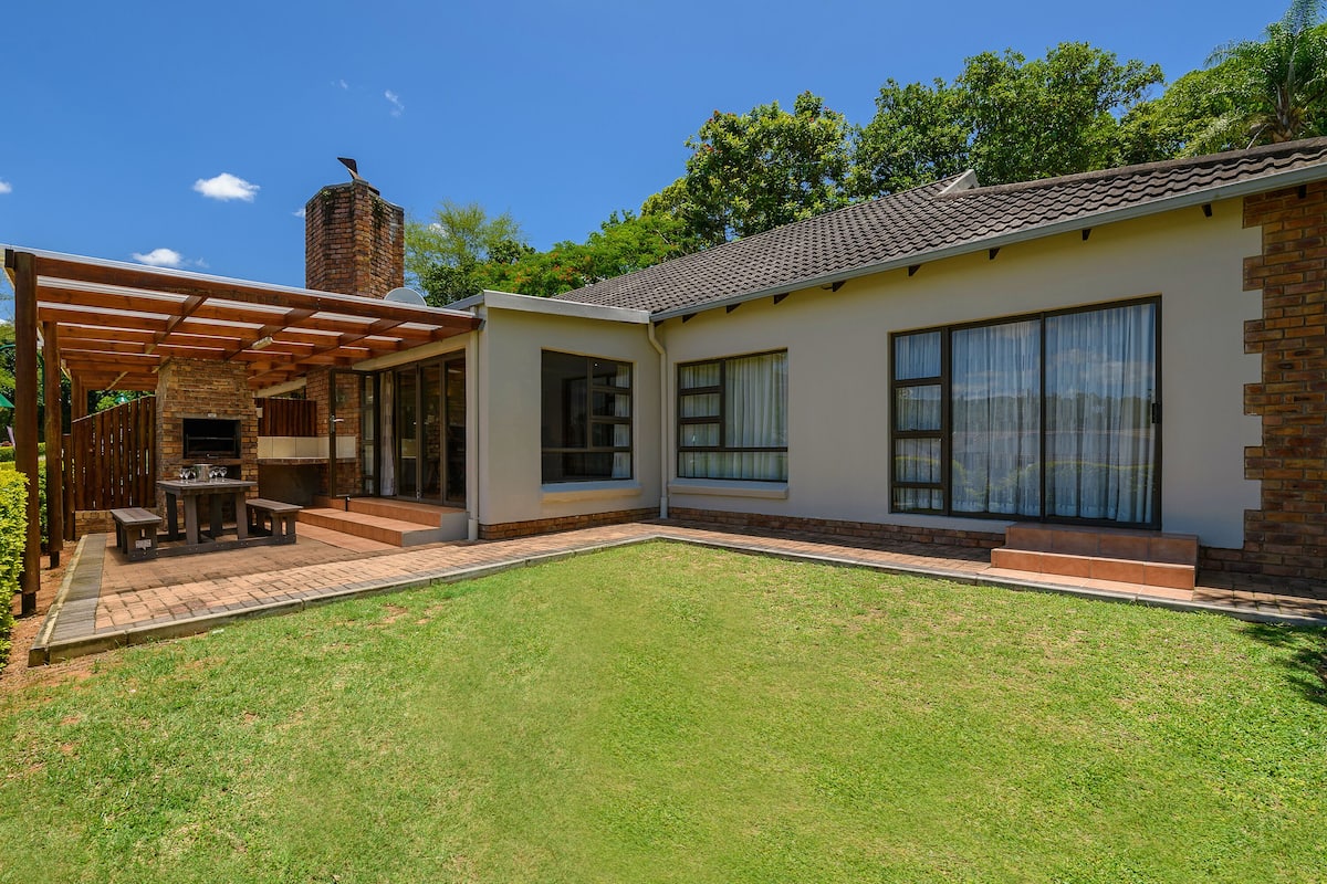 A modern house with a patio, a brick chimney, and large windows.