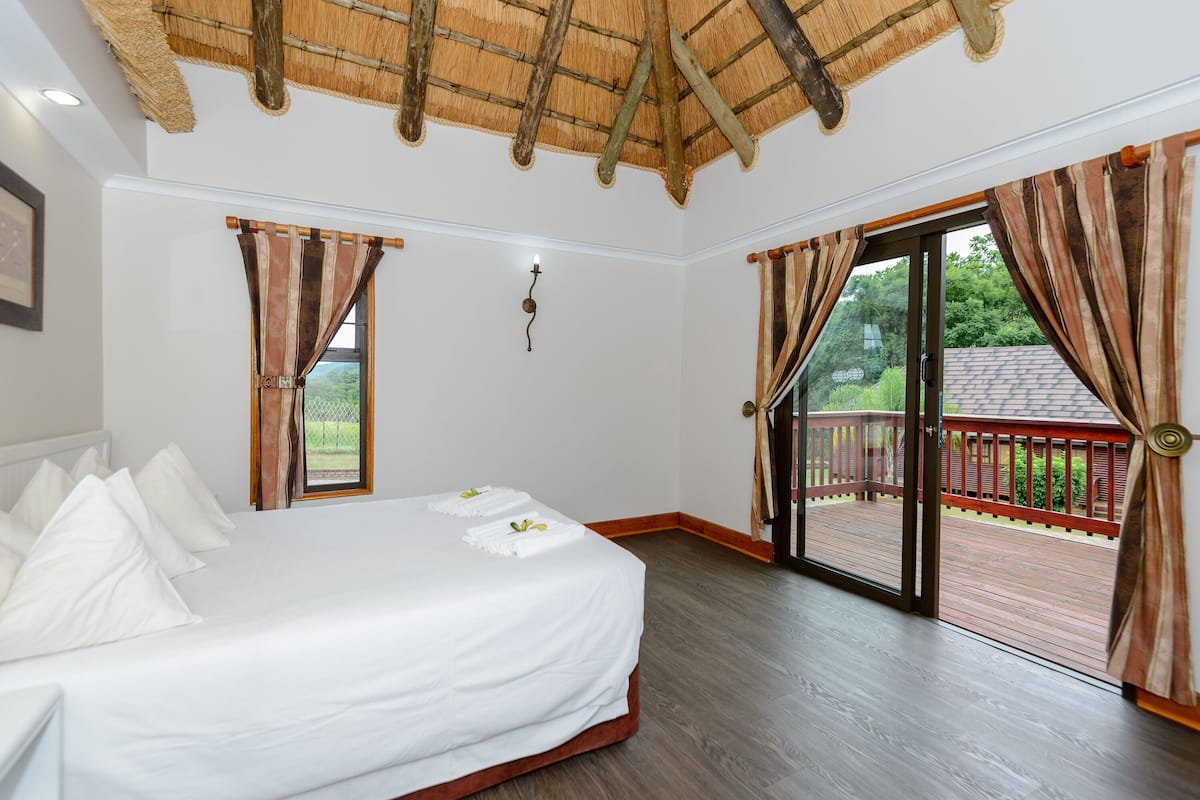 A bedroom with a bed, a large window, and a balcony.
