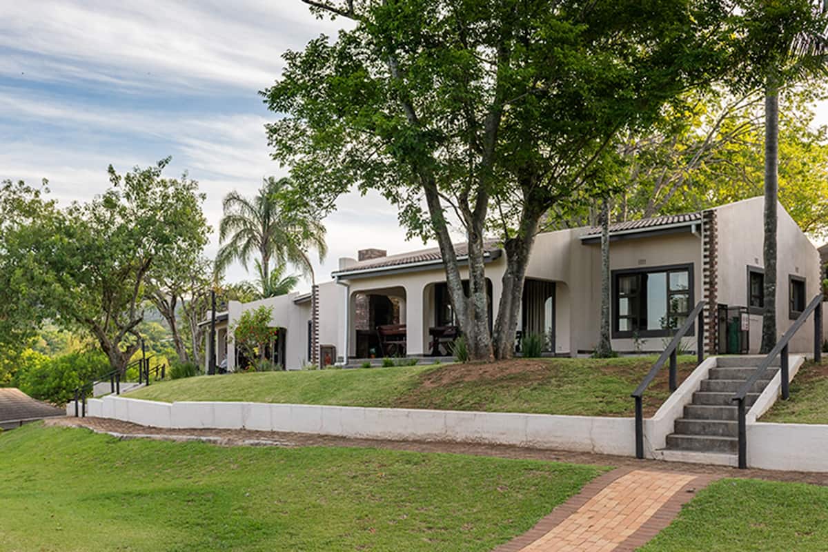 A modern house with a large front yard, a staircase, and a driveway.