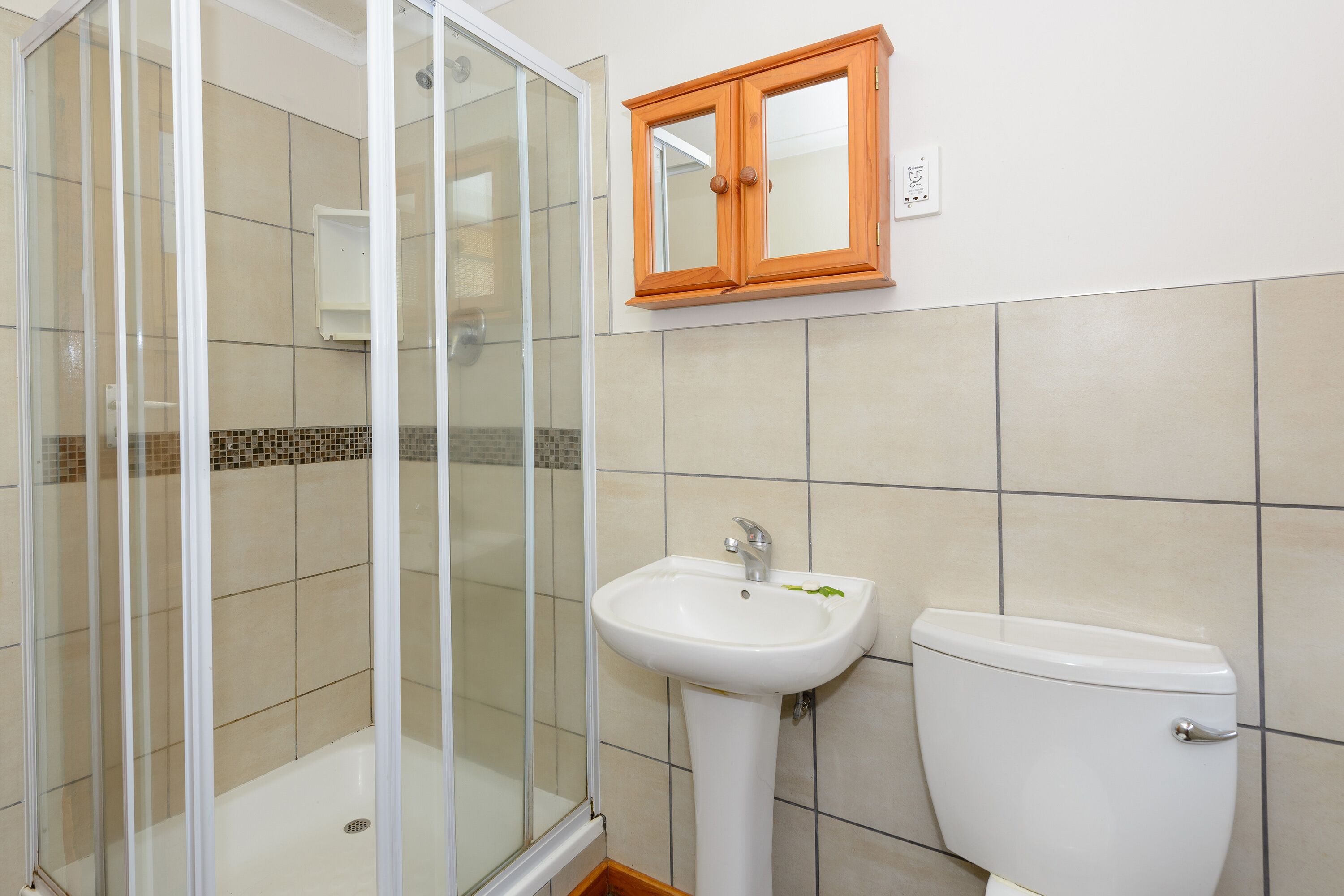 A bathroom with a glass-enclosed shower, a white sink, and a toilet.